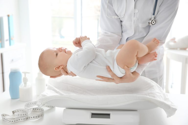 doctor examining baby on scales in room